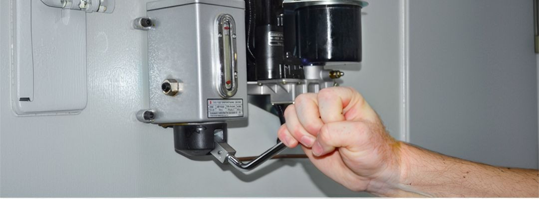 Technician adjusting a control valve on a hydraulic overload monitoring unit.